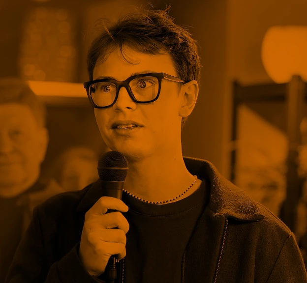 Bild von Valentin Kiefl mit einem Mikrofon in einem Orange Farbton
